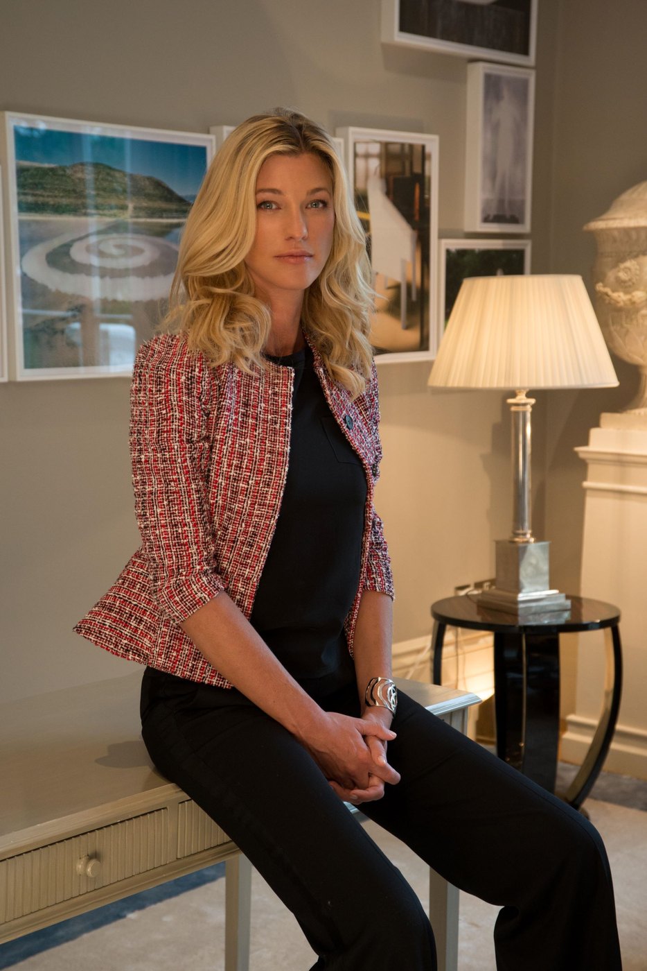 Nicole Junkermann sentada com um casaco de tweed numa sala tranquila, a olhar para a câmara