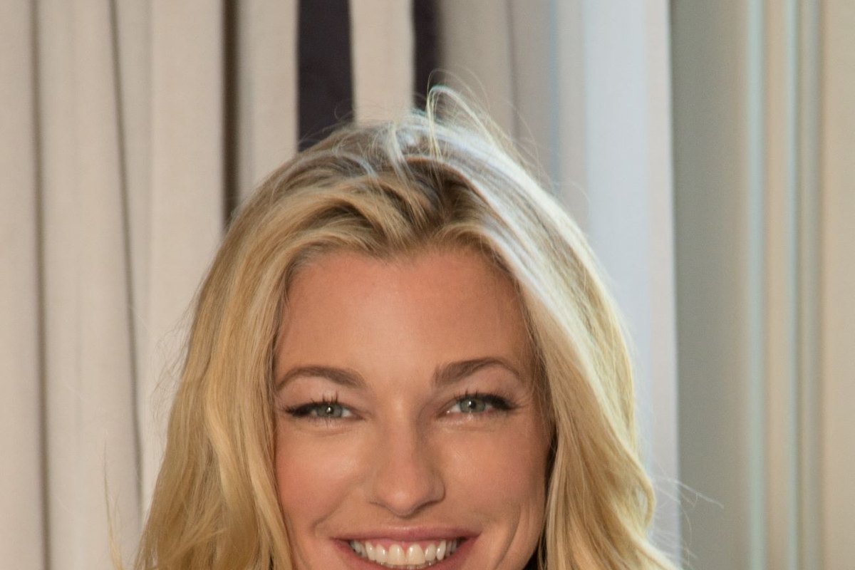 Nicole Junkermann smiling in a bright portrait with pale curtains behind her